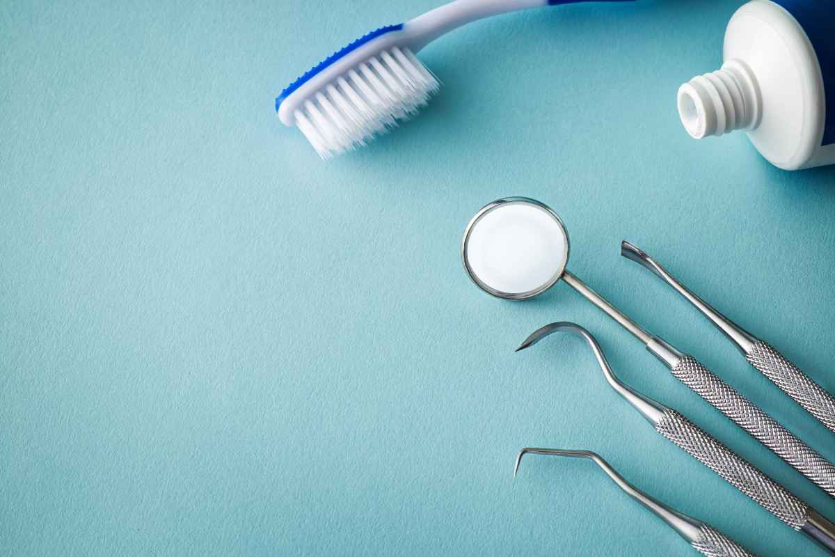 Cepillo dental, pasta e instrumental odontológico sobre fondo azul